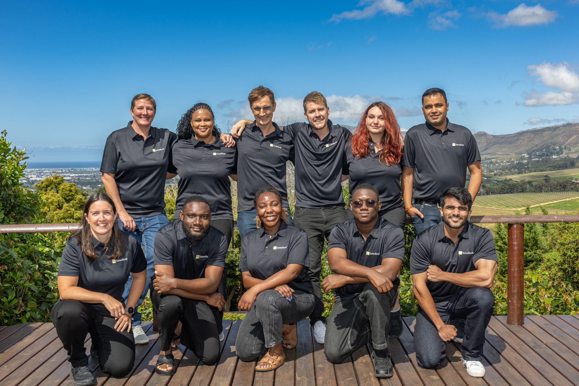SalesRook team group photo on a deck with mountains in the background